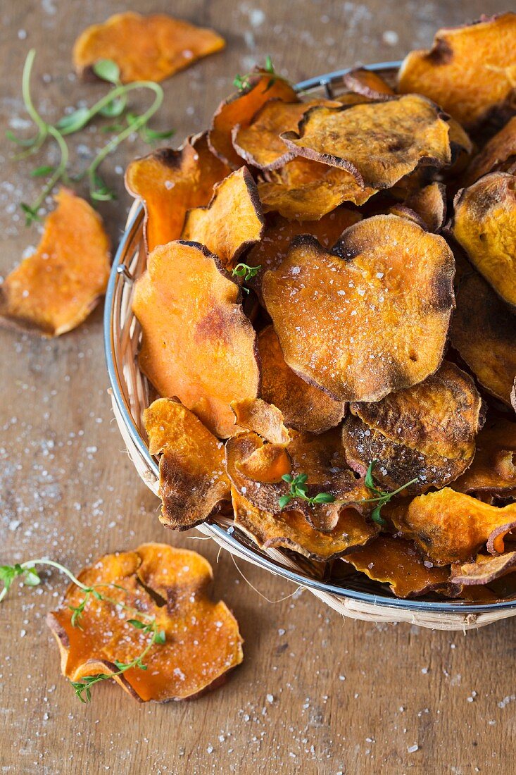 A pile of sweet potato crisps with fresh thyme and salt