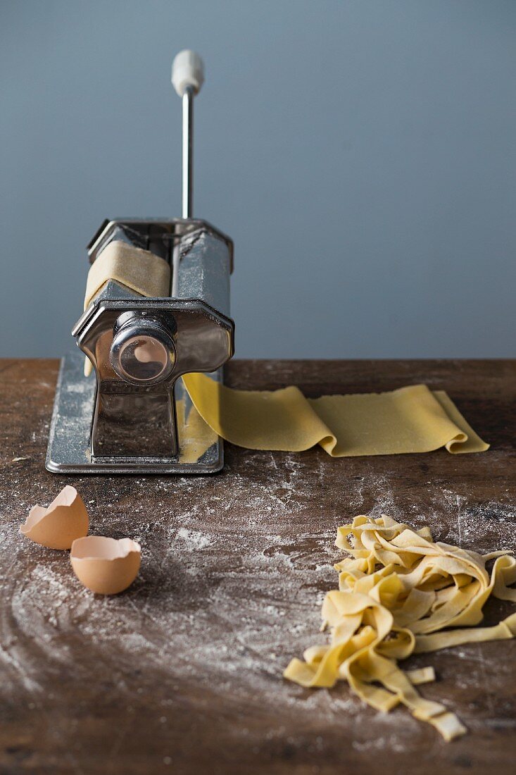 A pasta machine with fresh pasta dough and homemade tagliatelle
