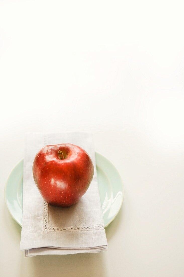 Ein roter Apfel mit Stoffserviette auf Teller