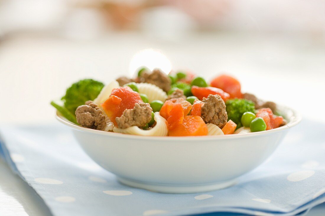 Shell pasta with minced beef, carrots, peas, broccoli and tomatoes