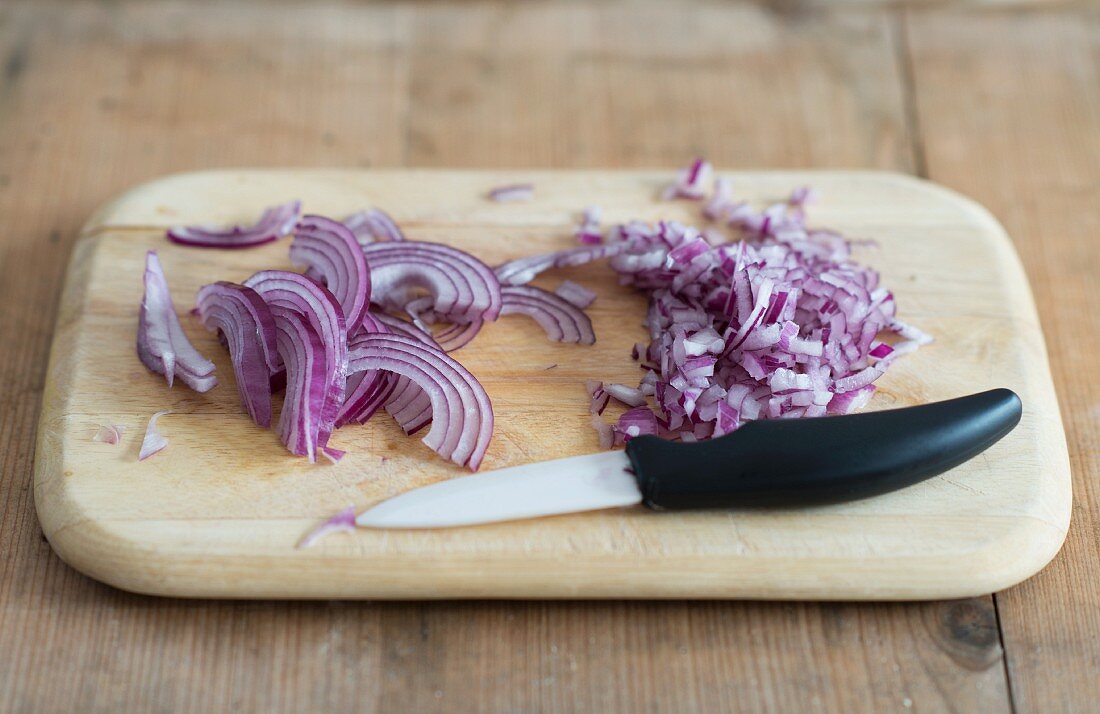 Red onions, sliced with a knife on a chopping board