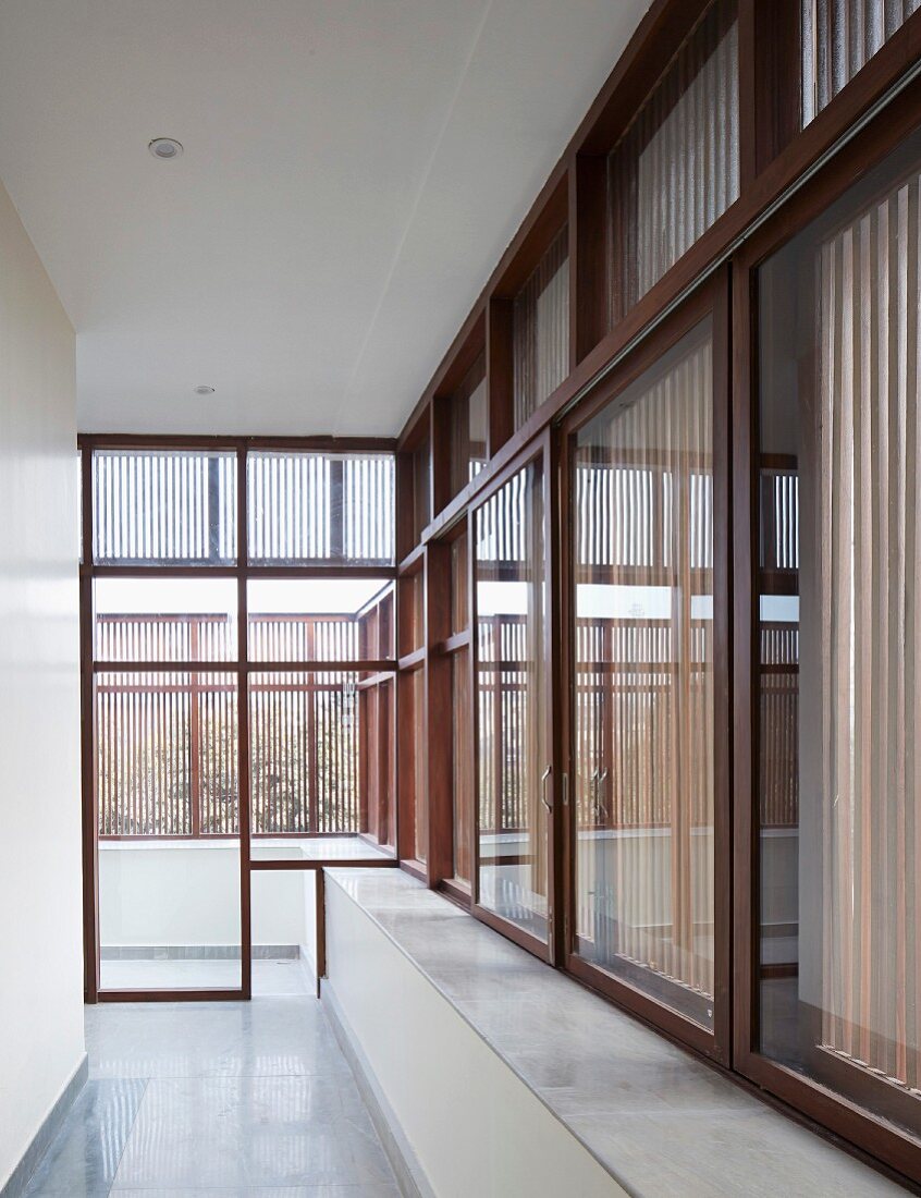 Corridor in modern Indian house with continuous, wood-framed glass wall