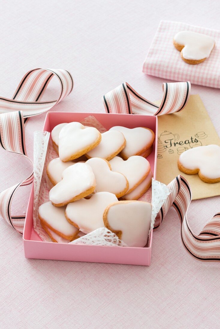 Heart-shaped biscuits with icing sugar in a pink box
