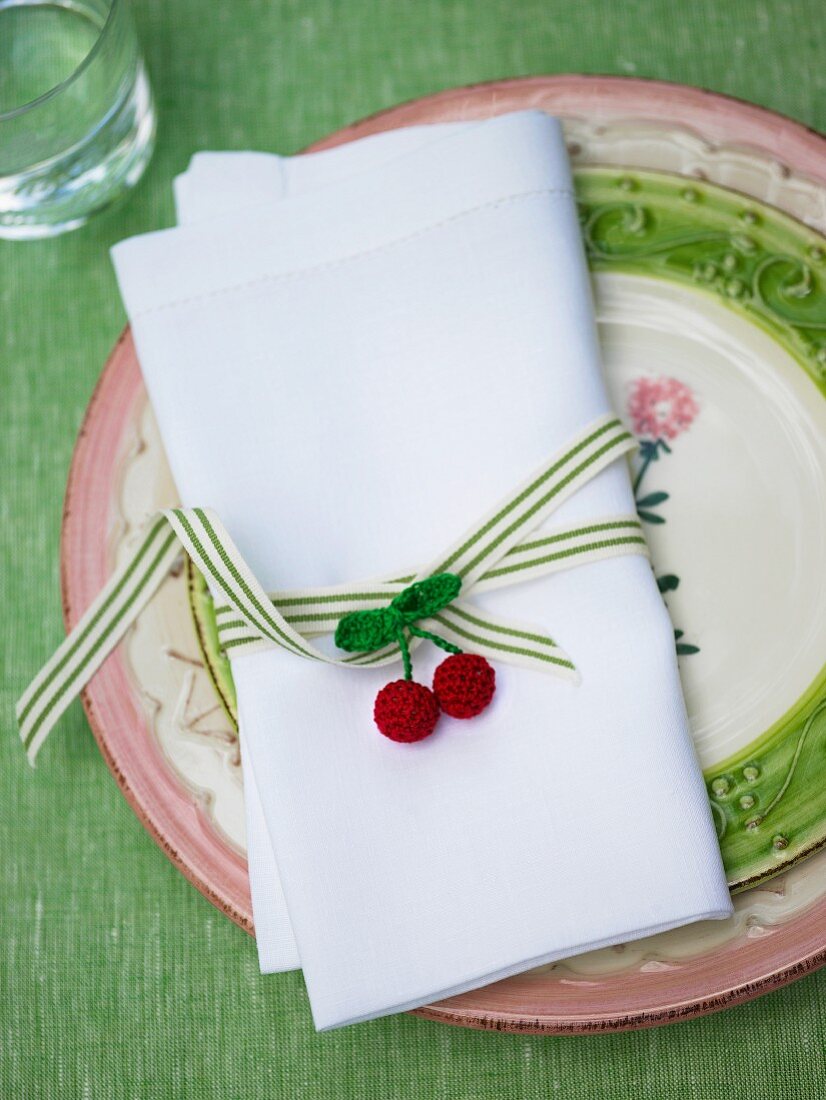 Linen napkin with ribbon and crocheted cherries on ceramic plate