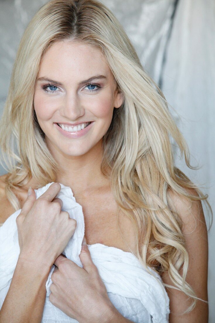 A young blonde woman holding a white towel in front of her body