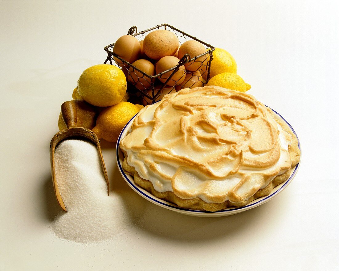 Lemon meringue pie with ingredients (sugar, eggs, lemons)