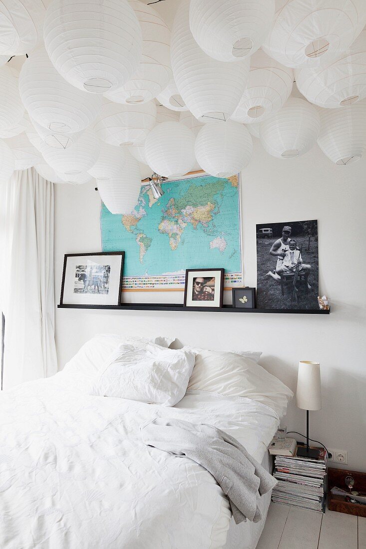 Double bed with white bed linen below a sea of paper lanterns on ceiling