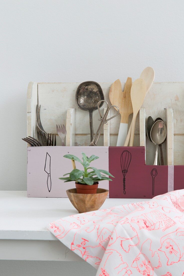 Cutlery and kitchen utensils sorted into hand-made and hand-painted cutlery boxes