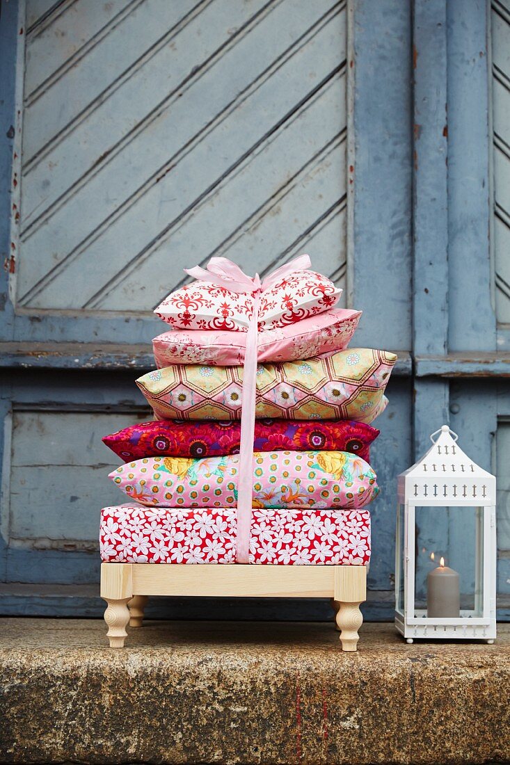 A stack of cushions on a foot stool next to a lantern