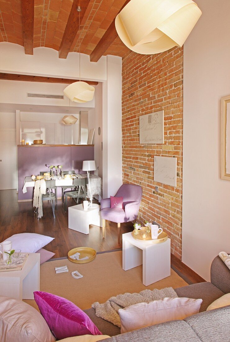 Lounge area with sofa and white side tables; dining table and counter in background in open-plan interior