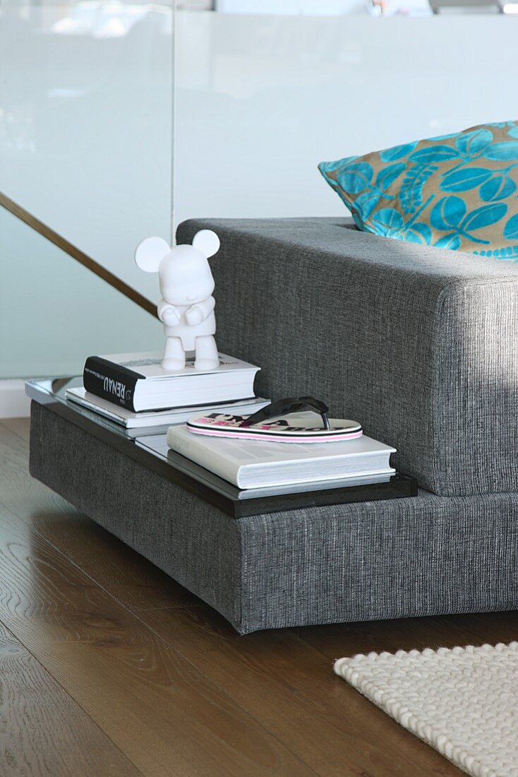 Stacked books and ornaments on upholstered shelf integrated into designer sofa