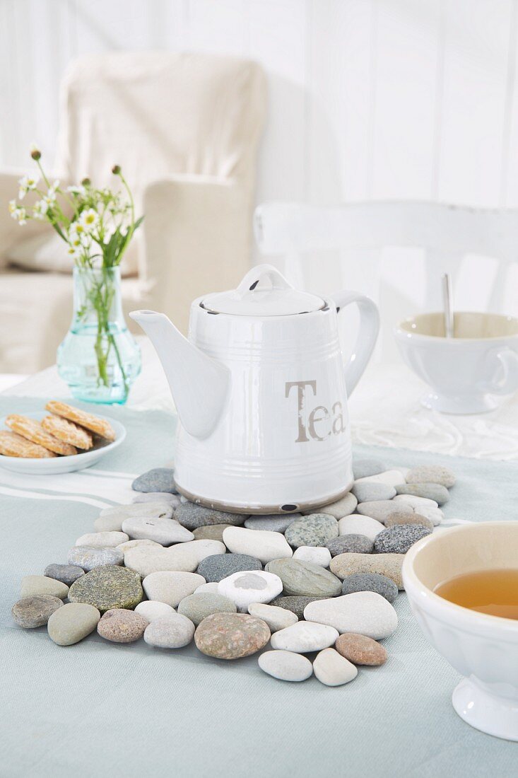 An enamel teapot on a pebble coaster