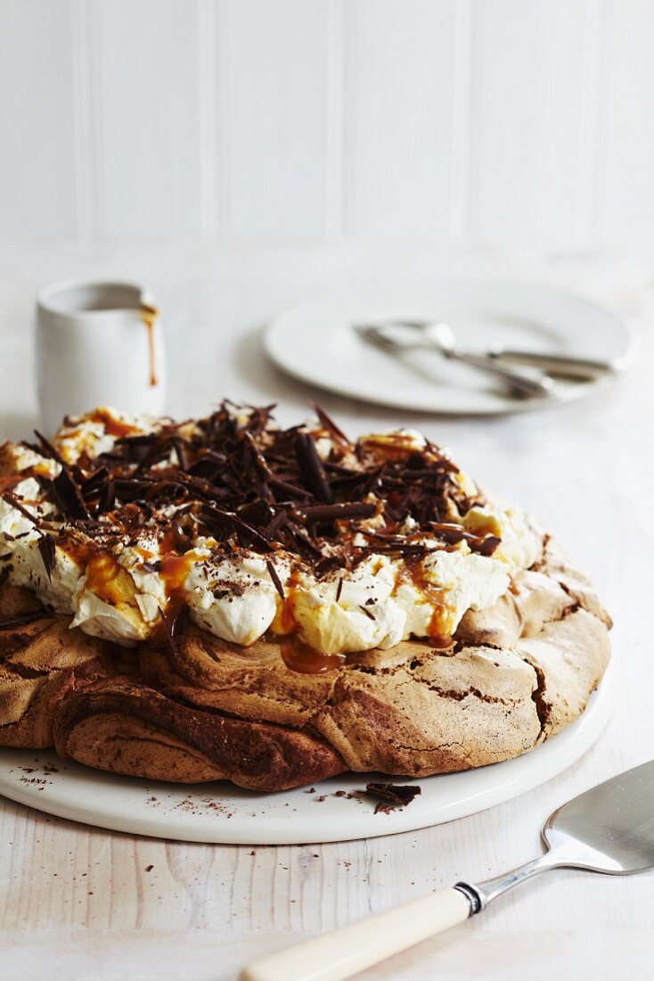 Chocolate meringue cake with cream, chocolate curls and caramel sauce