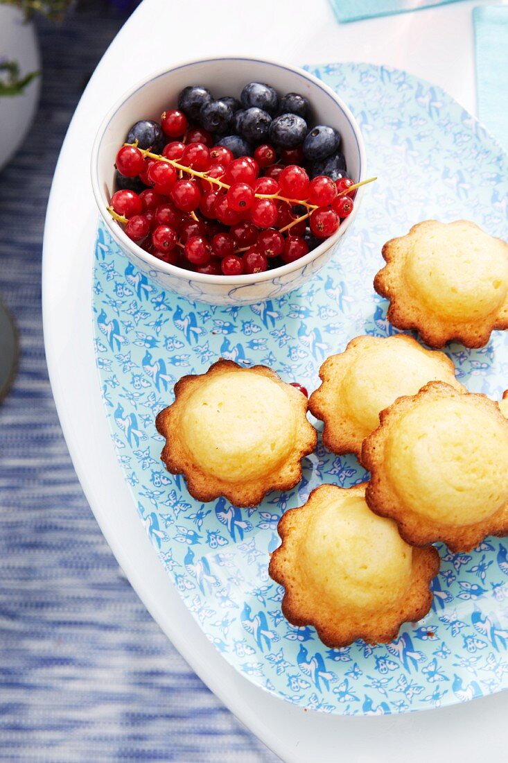 Summer berry fruits and muffins on a delicately patterned serving plate