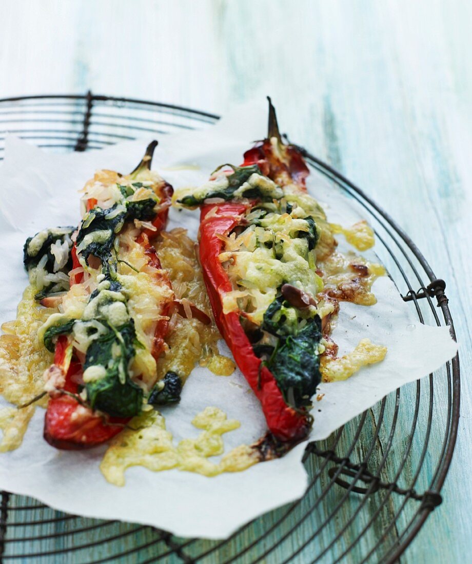 Pointed peppers filled with spinach and topped with melted cheese on a wire rack