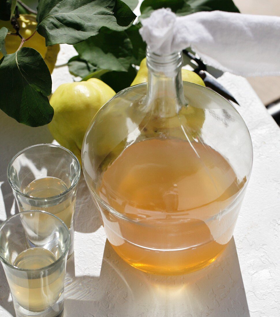 Homemade quince liqueur in a bulbous bottle with a fabric stopper