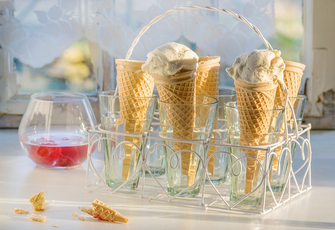 Homemade ice cream in cones in a cone holder in front of a kitchen window