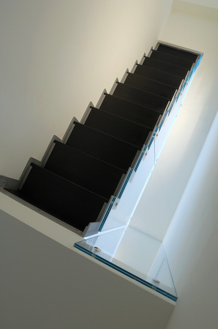 Blick von oben auf schwarze Treppe in weißem, minimalistischem Treppenhaus