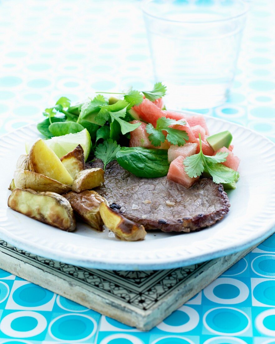 Roasted veal chop with roast potatoes served with a watermelon and avocado salad with coriander