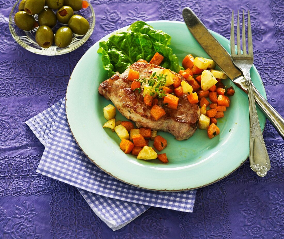 A pork chop with root vegetables and pineapples