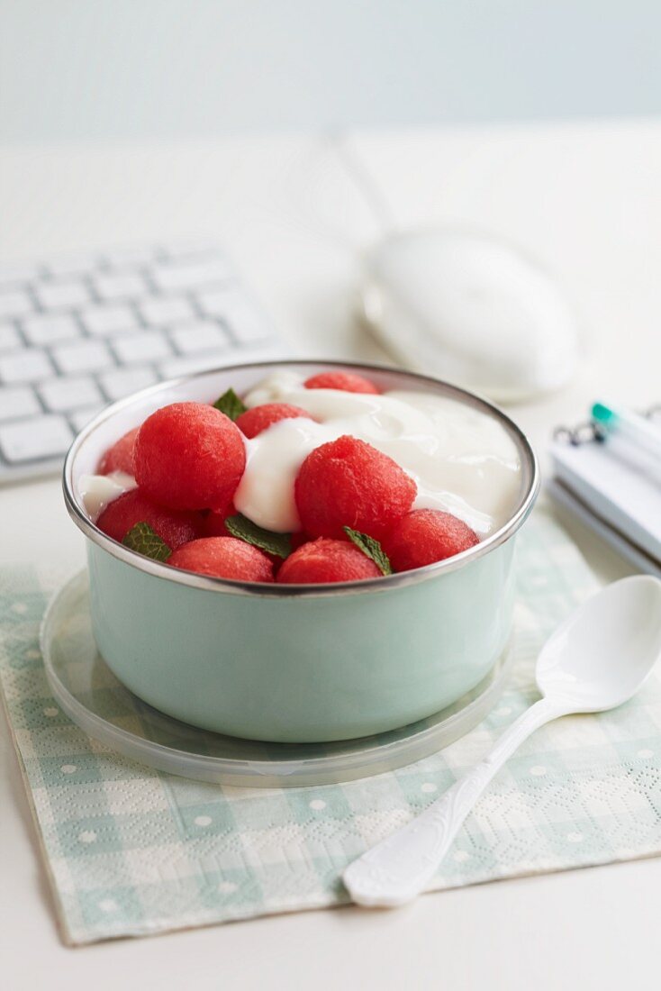 Melonenkugeln mit Joghurt und Minze auf einem Schreibtisch