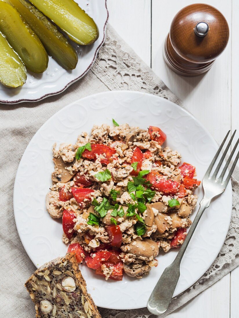 Scrambled tofu with vegetables served with flourless nut bread and gherkins