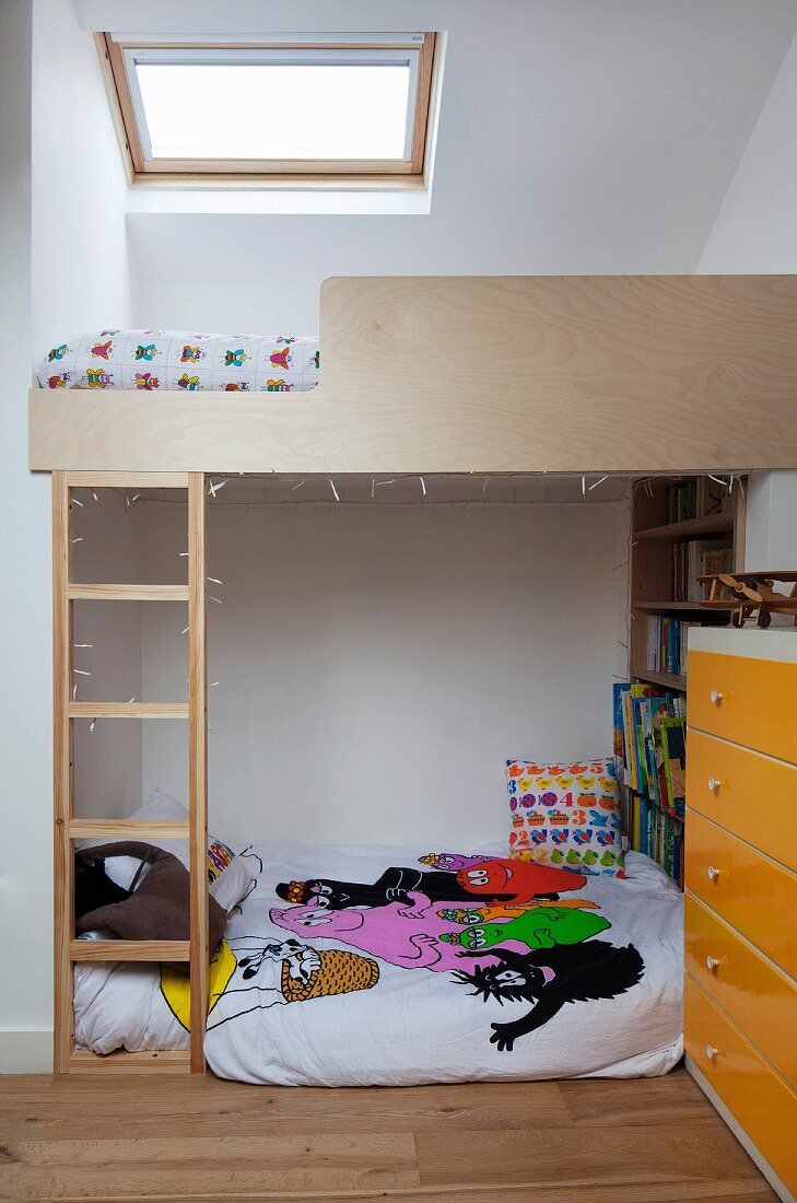 Kinderzimmer unter dem Dach - massgefertigtes Hochbett mit Leiter unter Dachflächenfenster, auf Boden Matratzenlager, seitlich Kommode mit gelben Schubladen