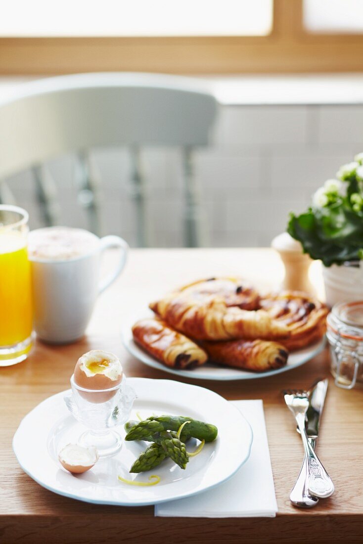 Breakfast of asparagus tips, a soft boiled egg, pain au chocolat, Danish pastry, orange juice and coffee