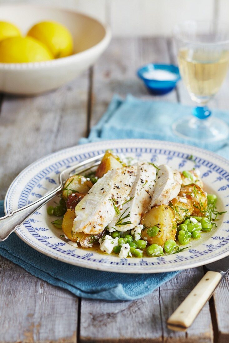 Chicken breast with lemon and pepper on a bed of potatoes with dill, feta cheese, peas and beans