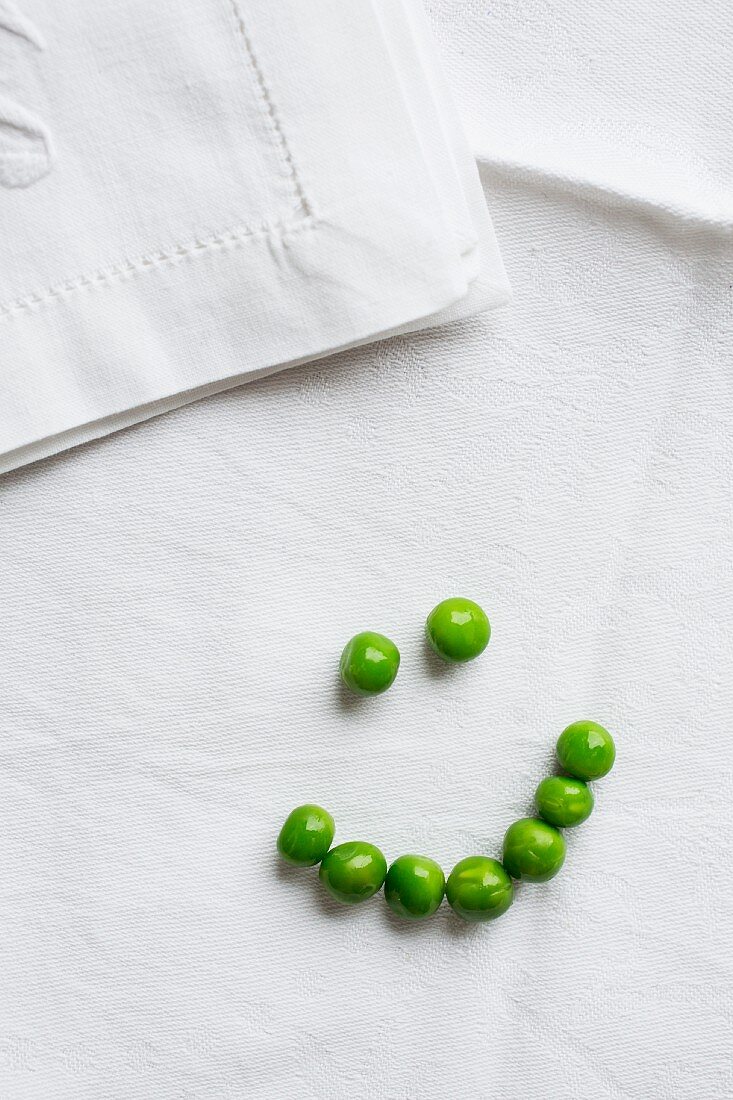 A pea smiley on a white tablecloth