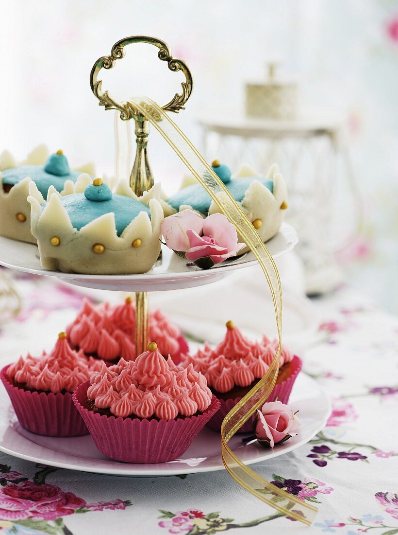 Cupcakes with pink cream and blue marzipan decorations on a cake stand