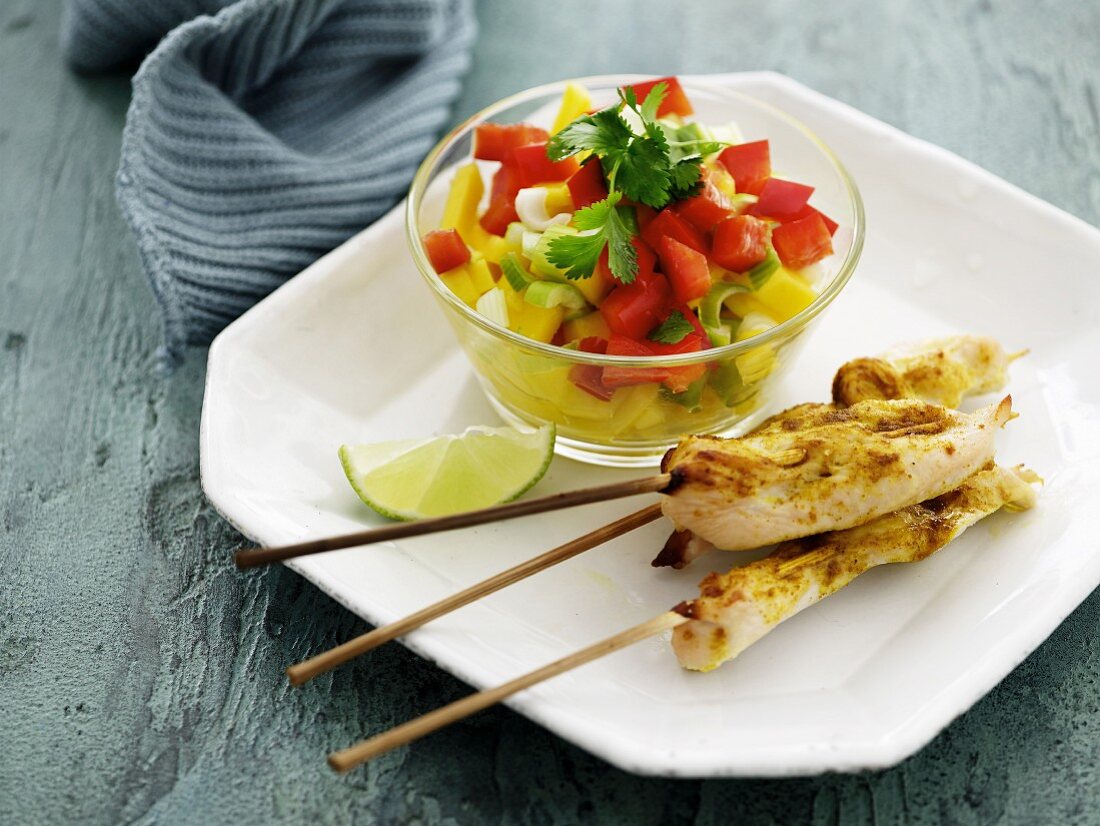 Chicken skewers with curry served with a mango and pepper salad with coriander