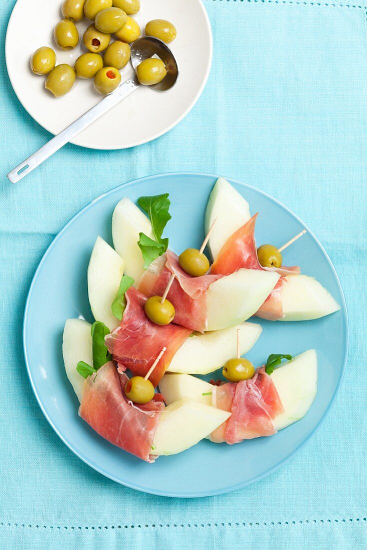 Melon slices with prosciutto and olives