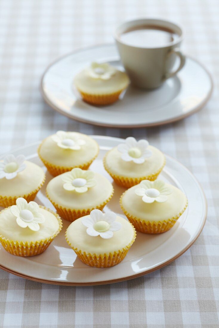 Fairy cakes decorated with sugar flowers served with a cup of tea