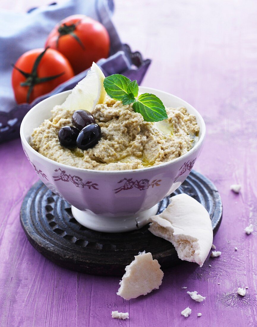 Hummus with olives, lemon and mint leaves