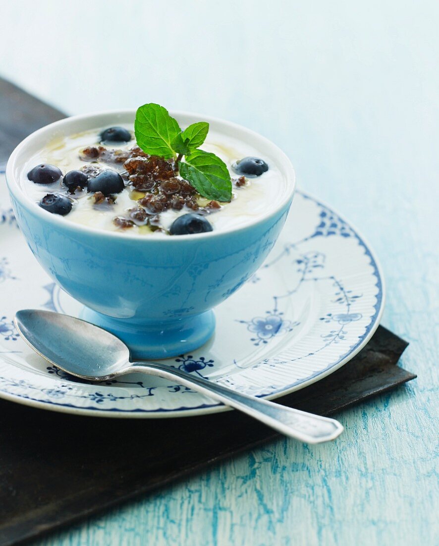 Joghurt mit Buttermilch, Honig, geröstetem Bauernbrot mit Ahornsirup, Blaubeeren und Zitronenmelisse.