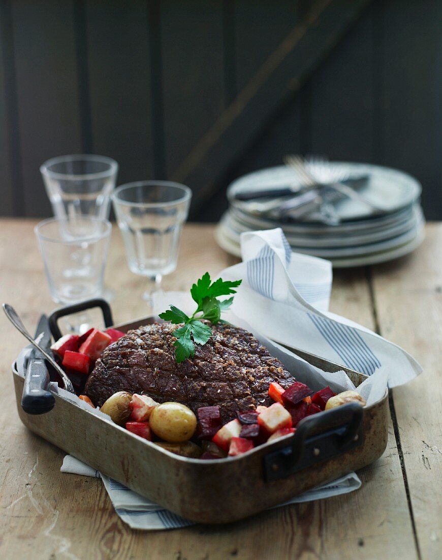 Roast lamb with beetroot and potatoes in a roasting tin