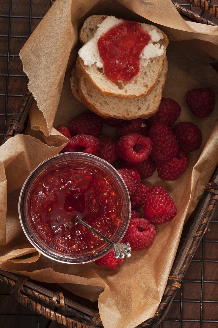 Homemade raspberry and mango jam in a basket with slices of bread and fresh raspberries