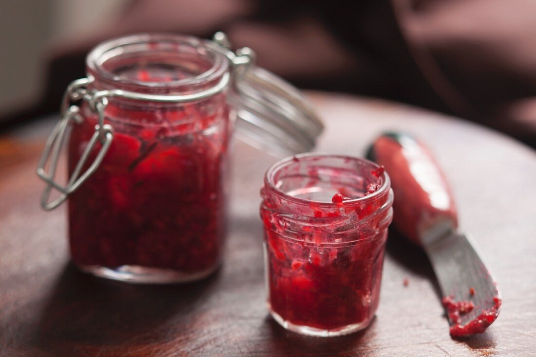 Two jars of raspberry jam with a knife