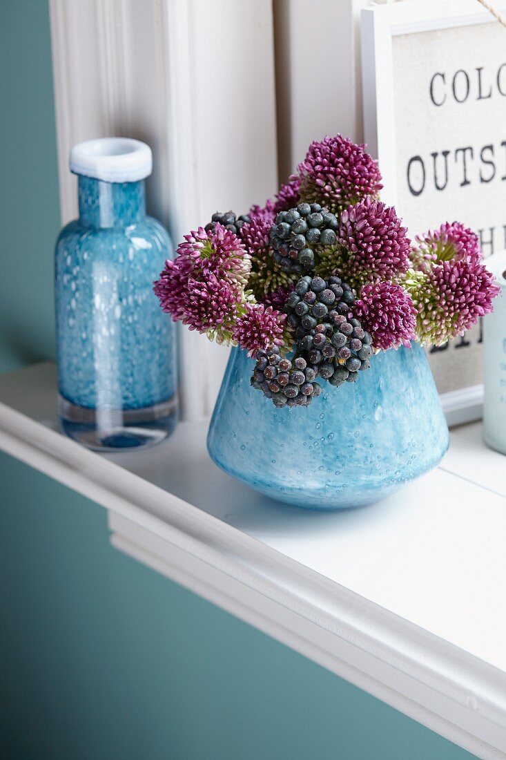 Allium flowers and ivy berries in vase