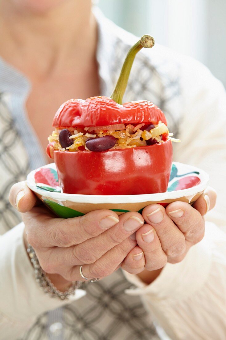 A woman holding a stuffed pepper on a plate