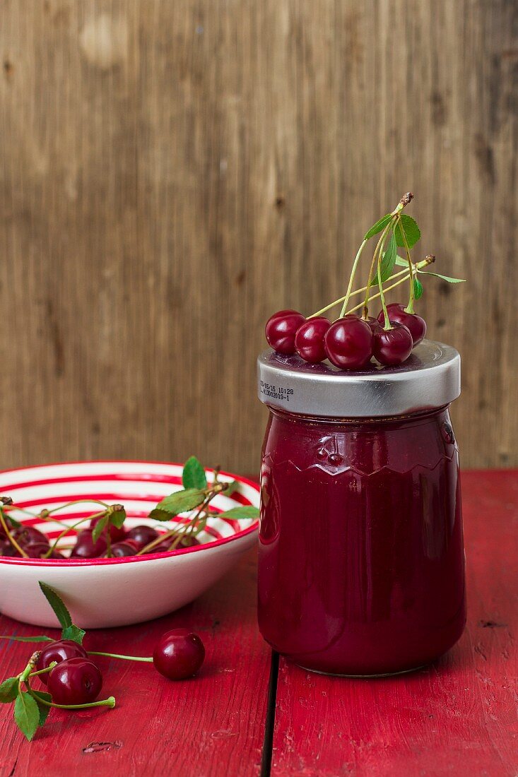A jar of cherry jam and fresh cherries