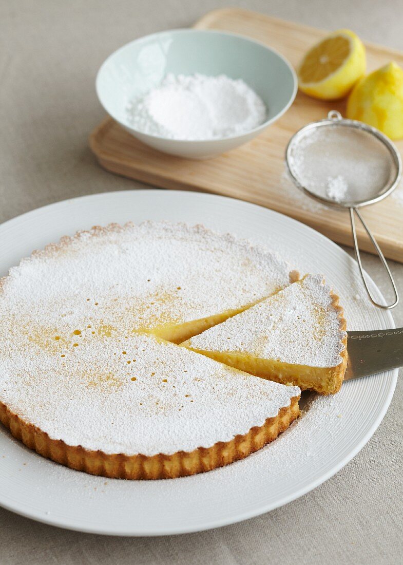Lemon tart with icing sugar, sliced