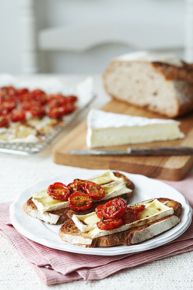 Slices of white bread topped with brie and roasted cherry tomatoes