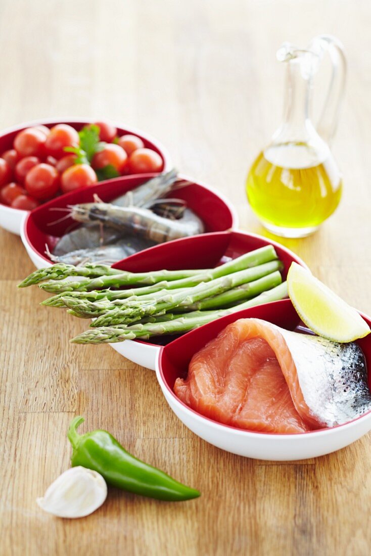 A bowl of ingredients: tomatoes, prawns, asparagus and salmon fillet