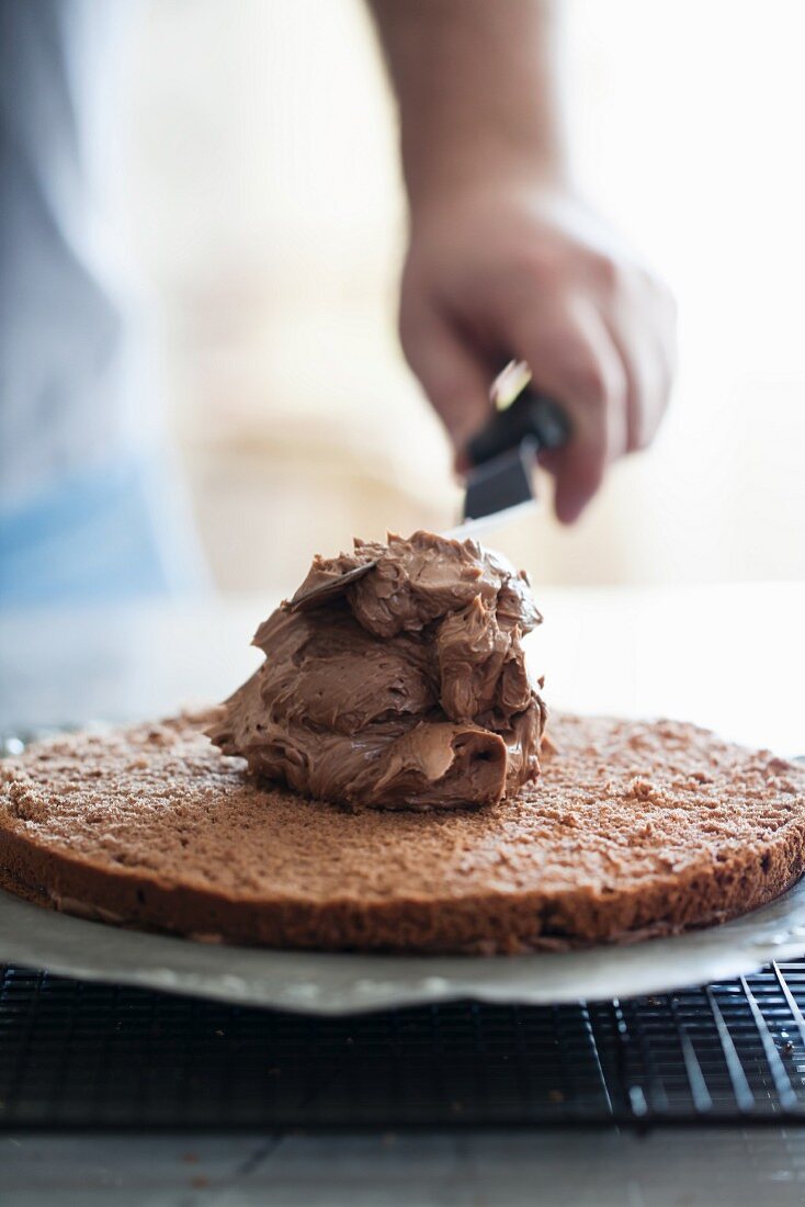 Chocolate cream being spread on a cake base