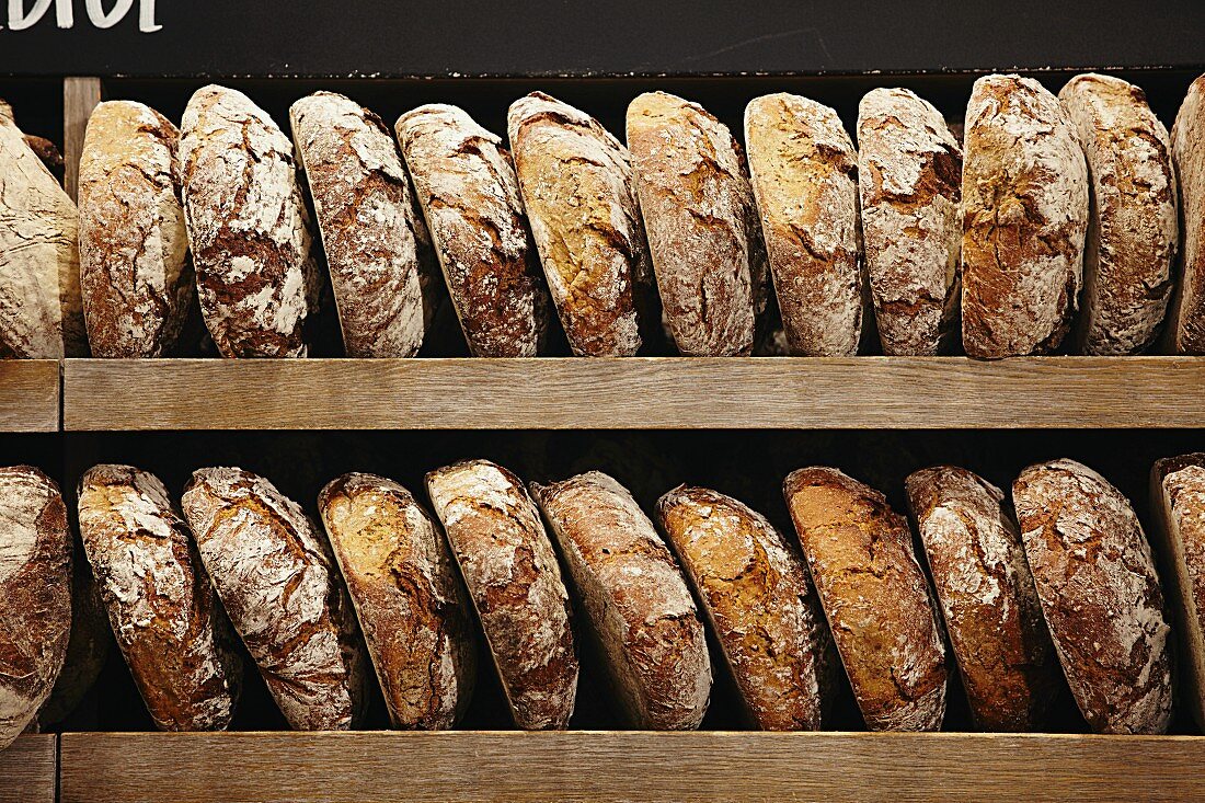 Loaves of organic bread on a wooden shelf in a bakery