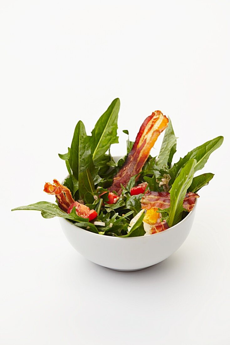 Dandelion leaf salad with tomatoes, hard-boiled eggs and fried bacon