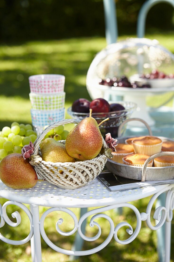 Früchte, Gläser & Muffins auf Metalltischchen im sommerlichen Garten