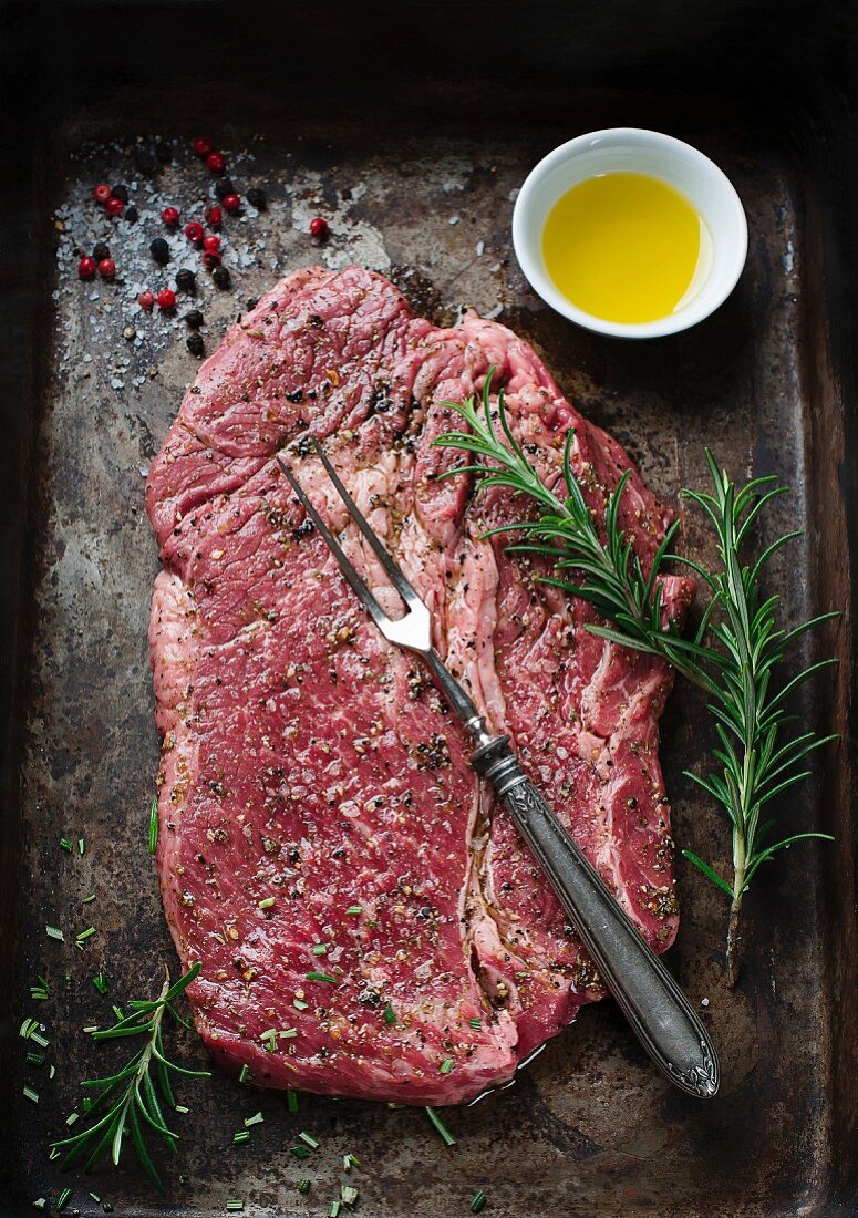 Raw, seasoned beef steak on a baking tray